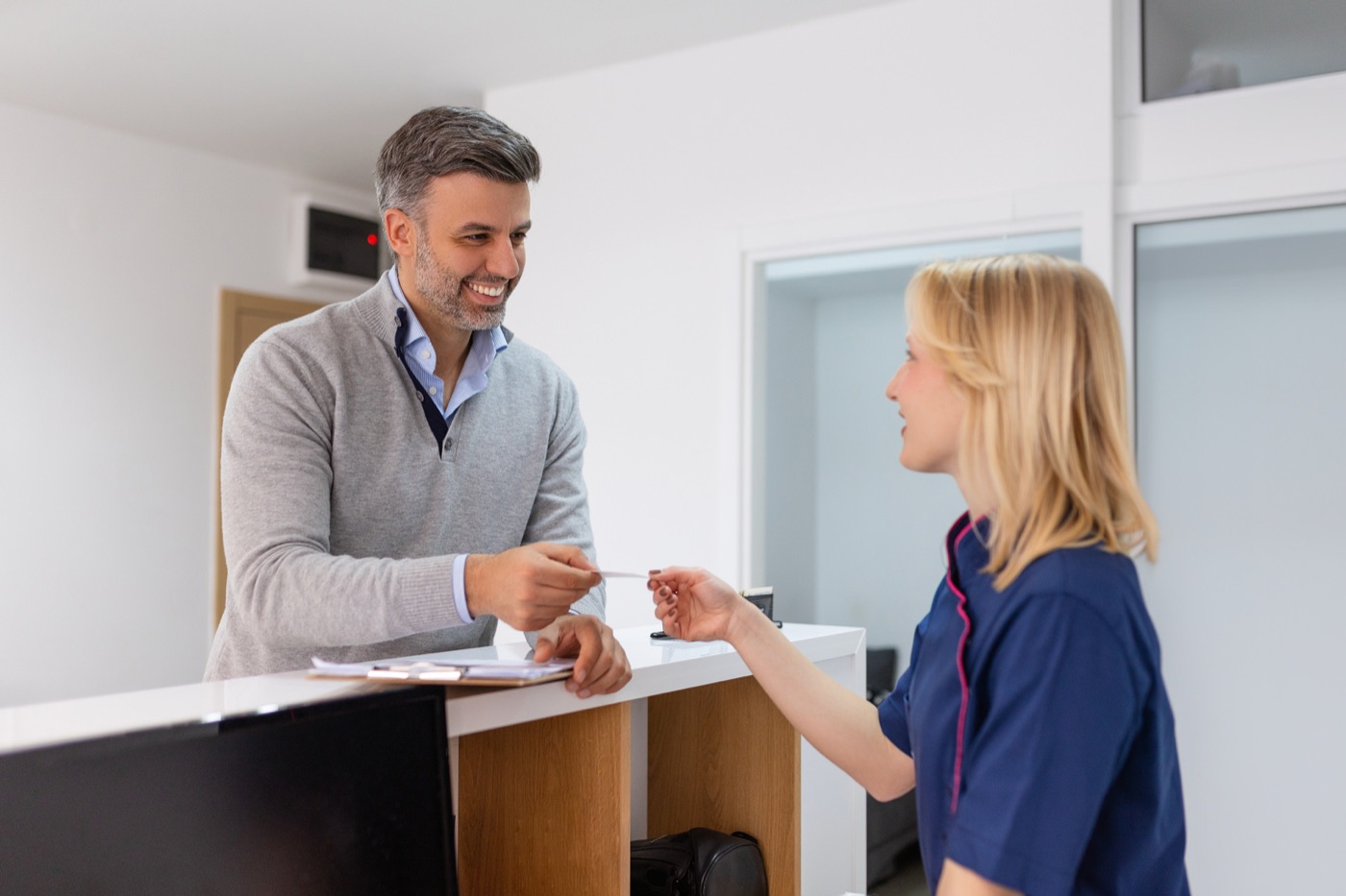 A patient checking in at a clinic front desk
