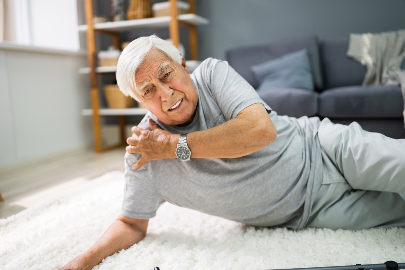 An older man on the floor holding his shoulder after a fall